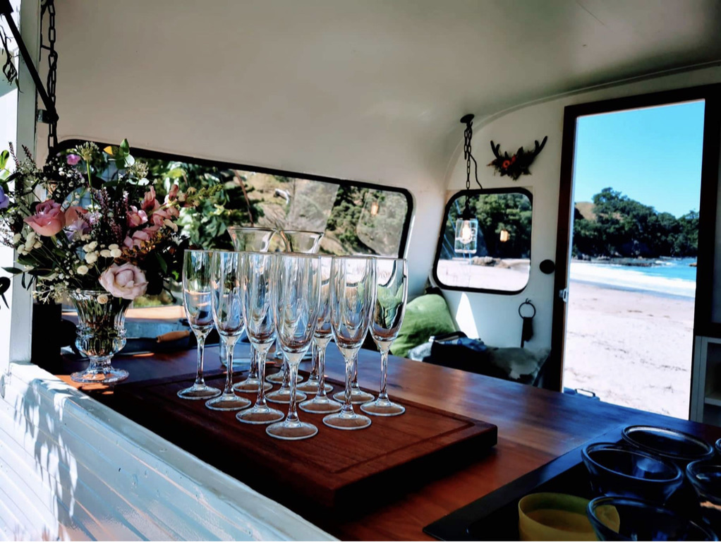 Champagne glasses and fresh flowers inside Vinnie overlooking the beach