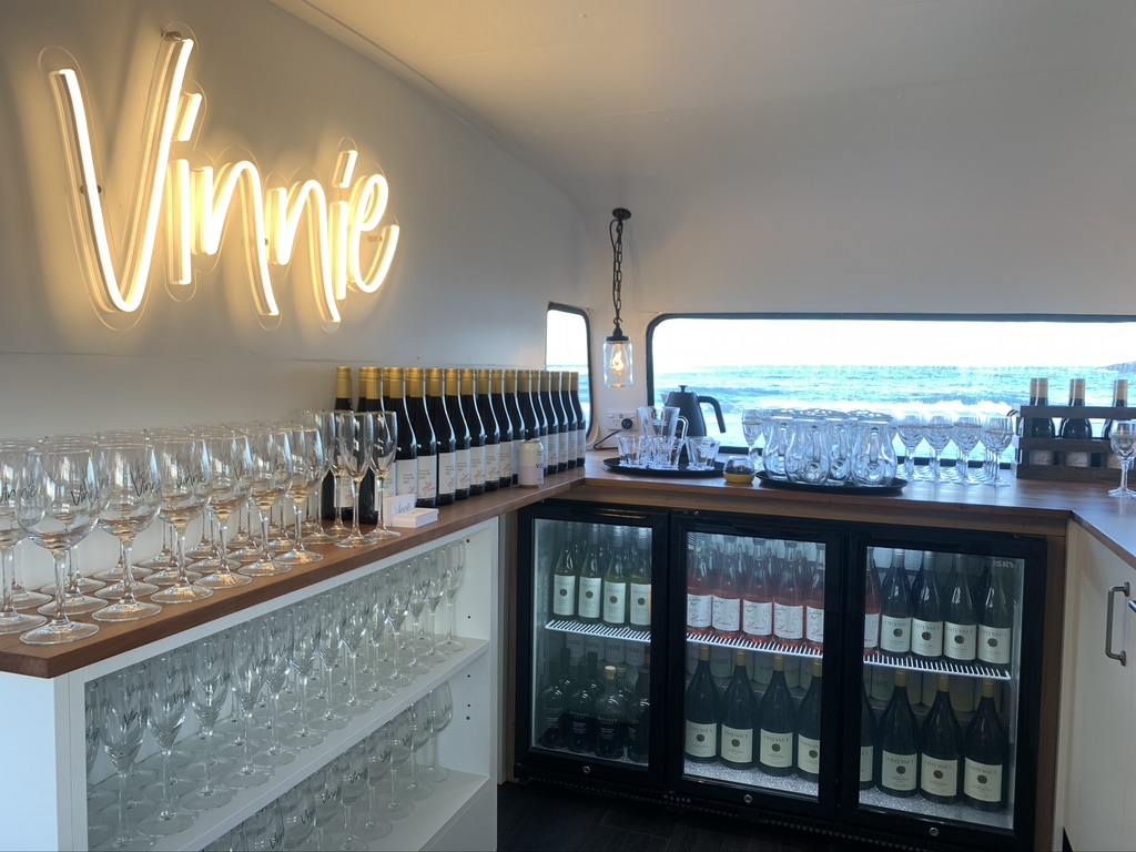 Vinnie's neon sign above rows of glassware and chilled wine bottles