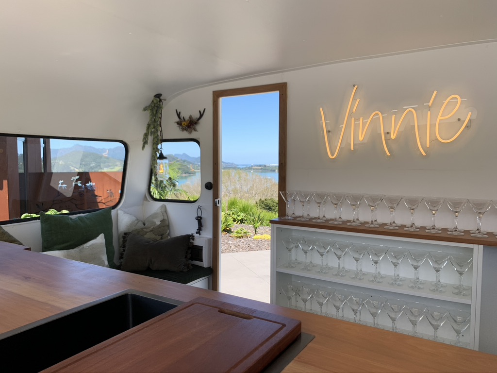Vinnie's interior styled with martini glasses and a warm neon sign, overlooking the water