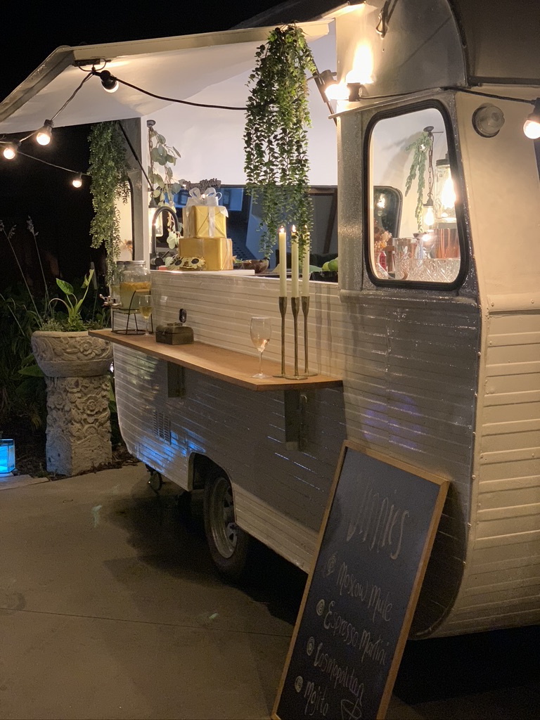 Vinnie the caravan bar lit with candlelight and string lights at an evening private event